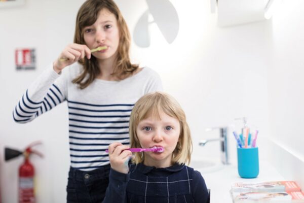 Image de deux petites filles se brossant les dents chez le dentiste pour leur première visite